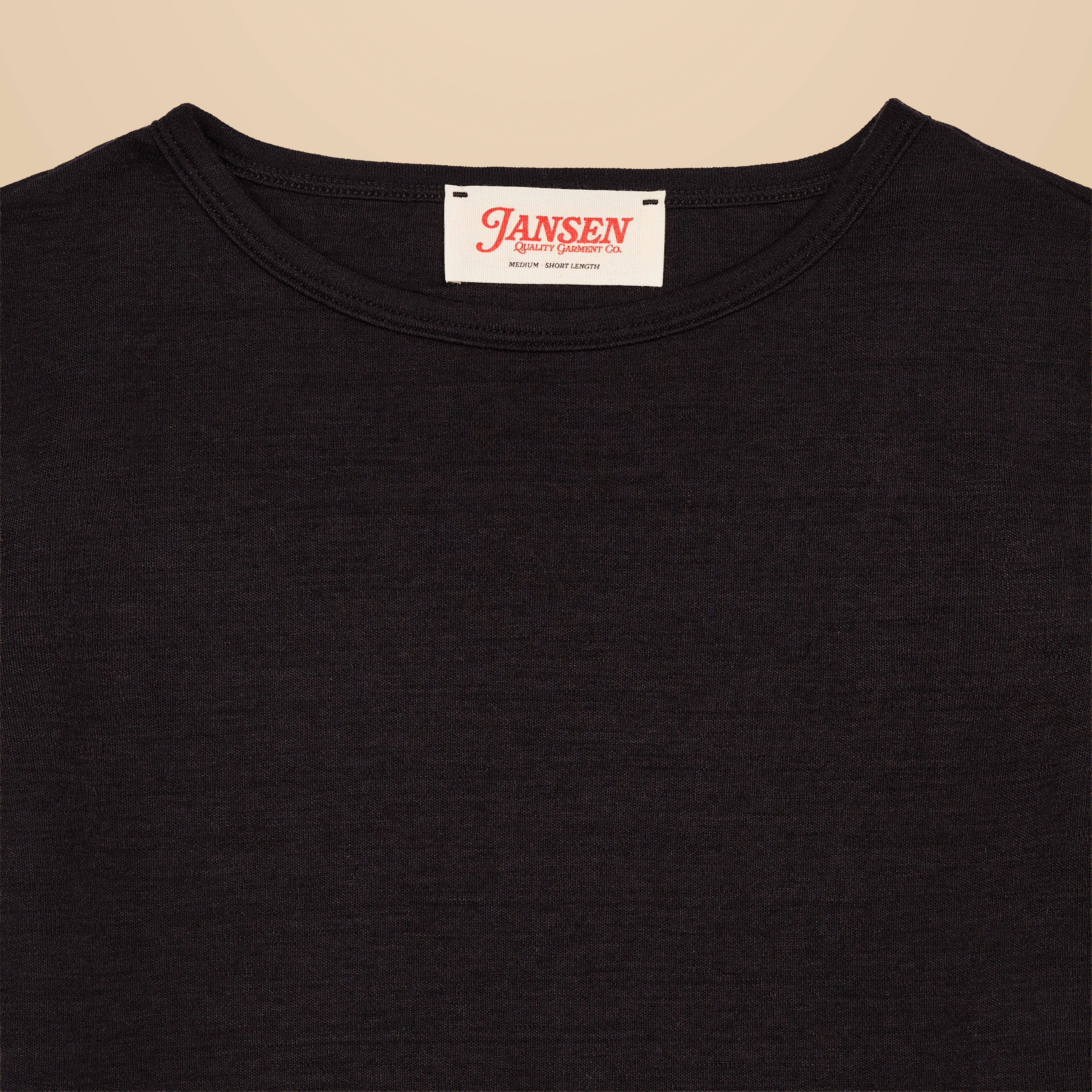 Black t-shirt with a visible brand label on a beige background