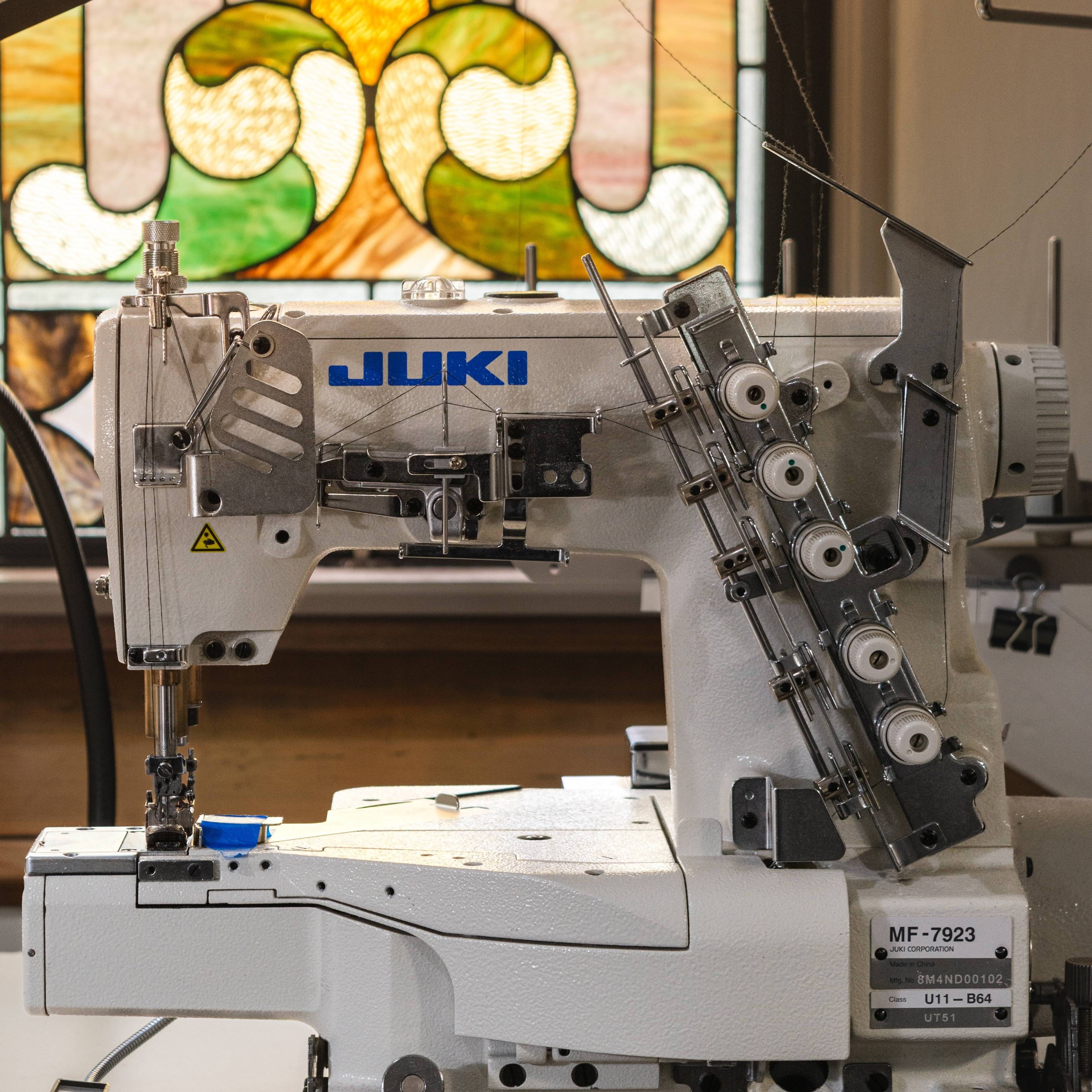 Sewing machine with 'Juki' branding in front of a stained glass window.