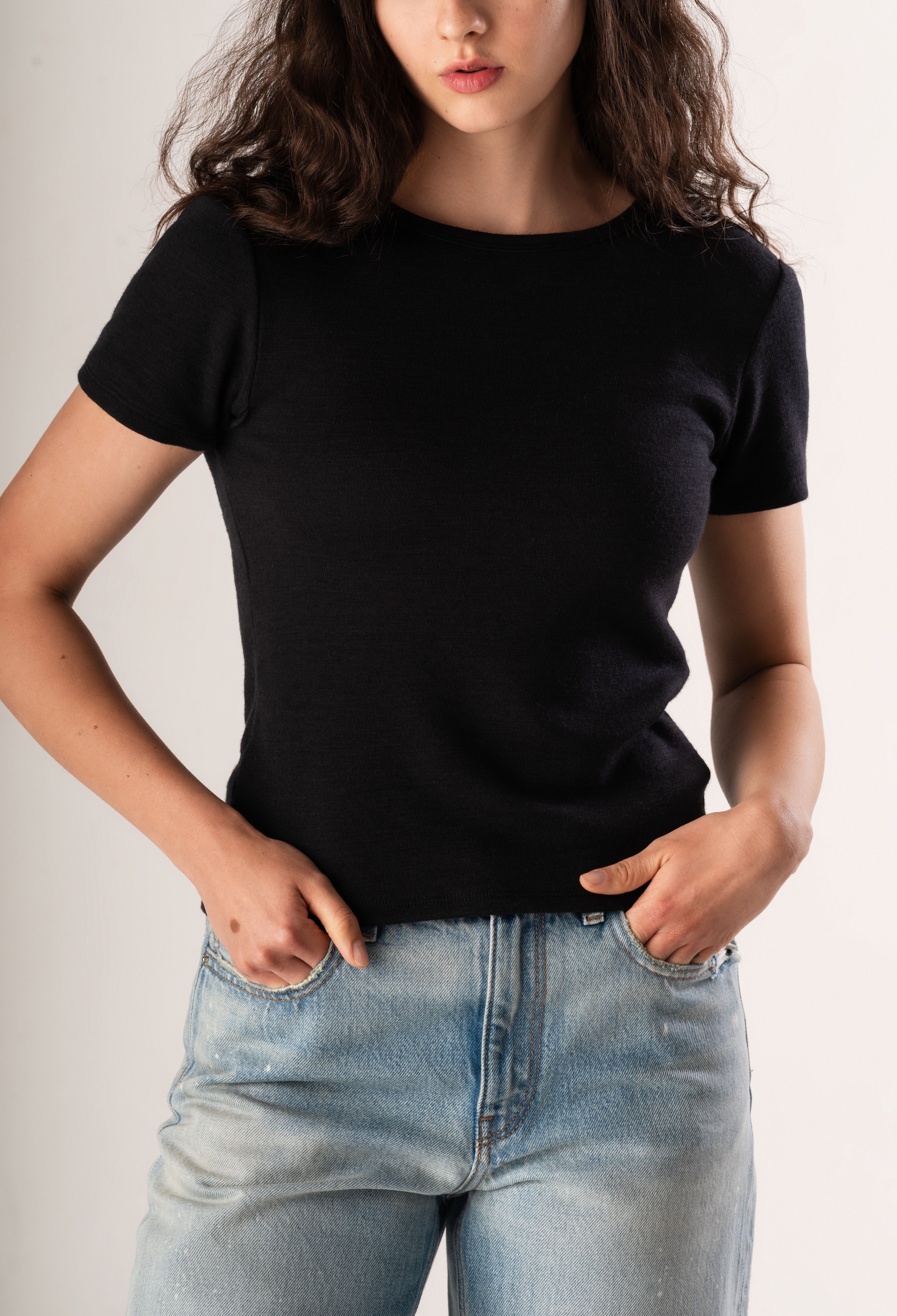 Person wearing a black t-shirt and light blue jeans against a neutral background