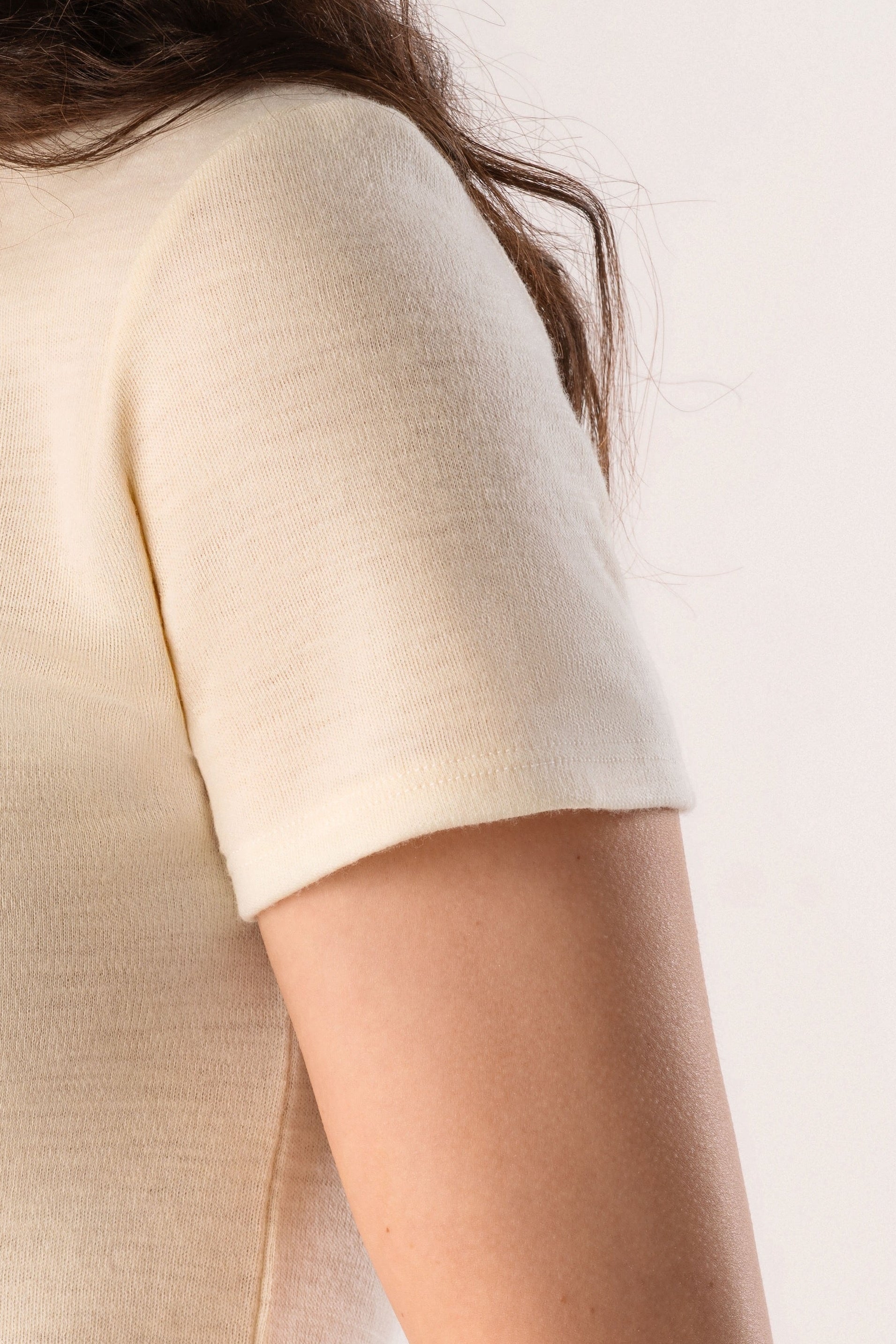 Person wearing a cream-colored t-shirt and blue jeans on a white background