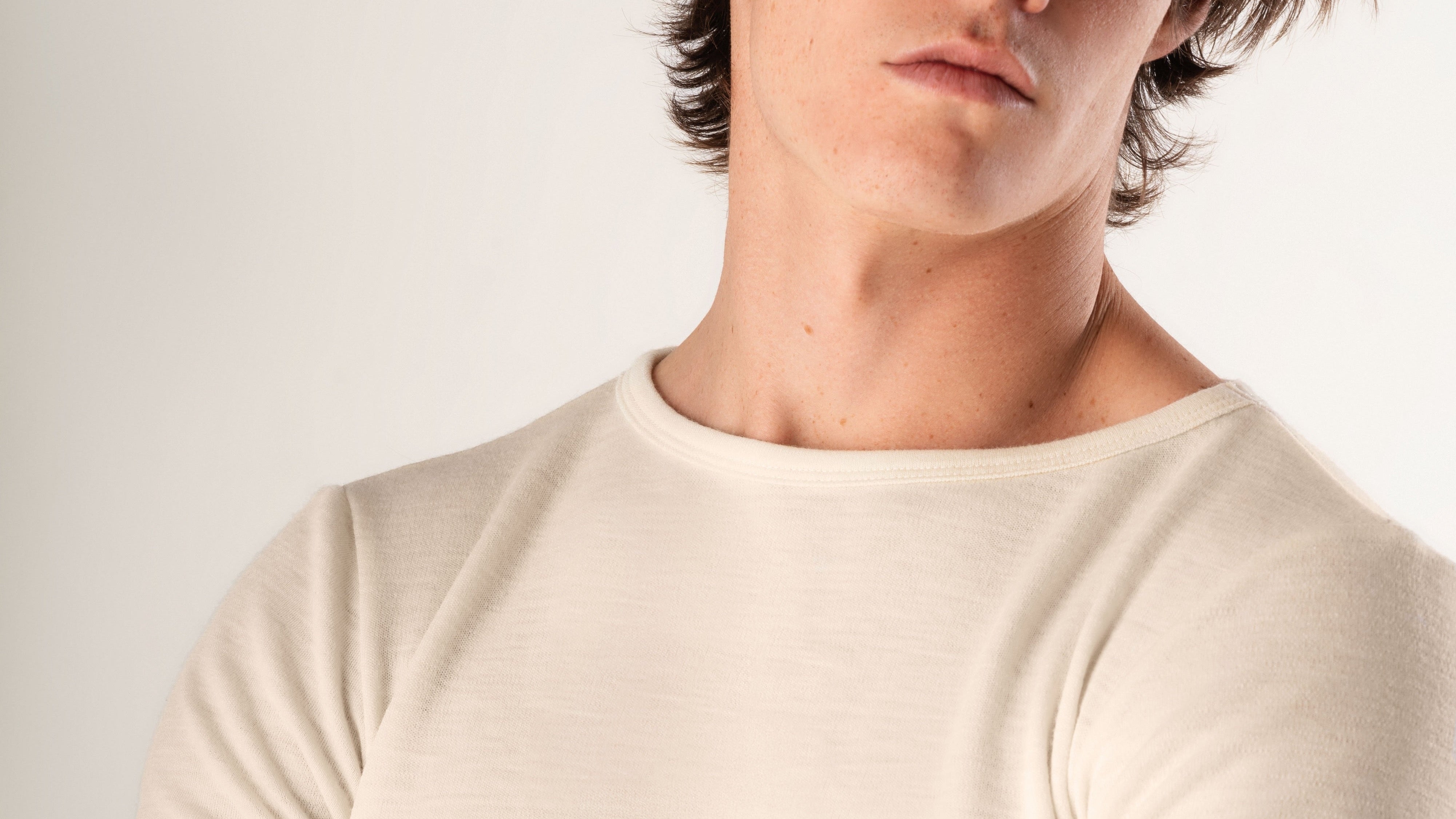 Man wearing a plain white t-shirt against a light background