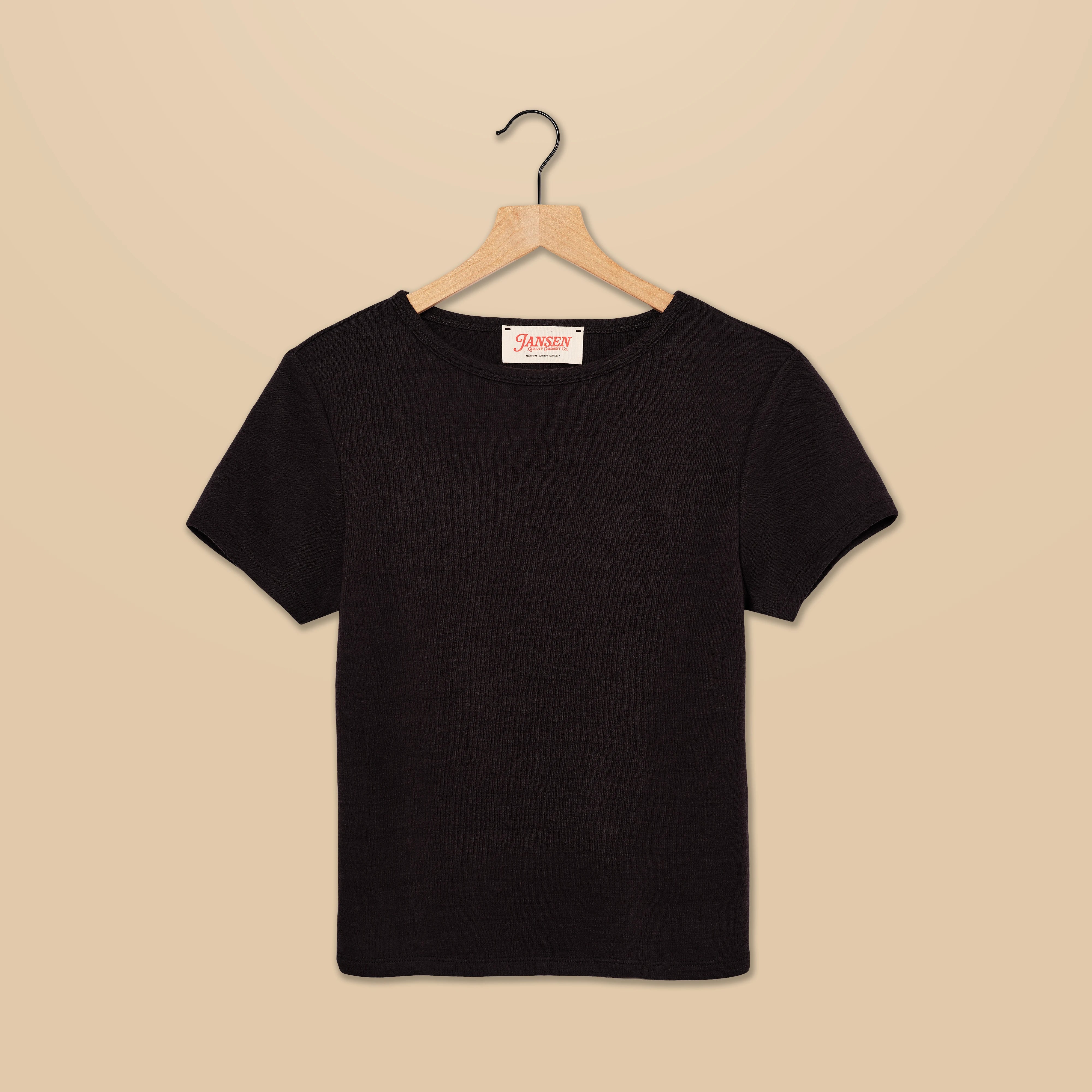 Black t-shirt on a wooden hanger against a beige background