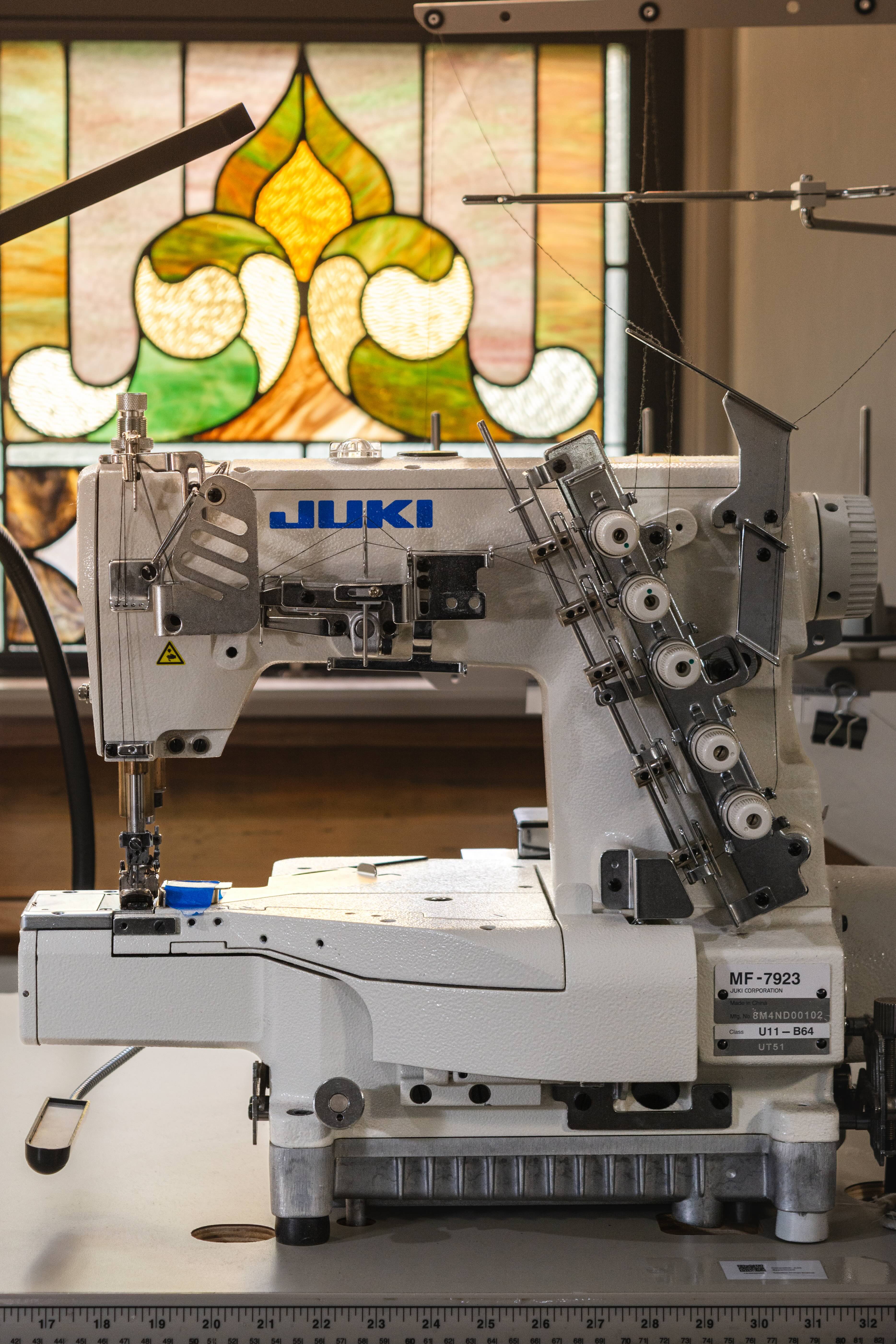 Sewing machine with 'Juki' branding in front of a stained glass window.