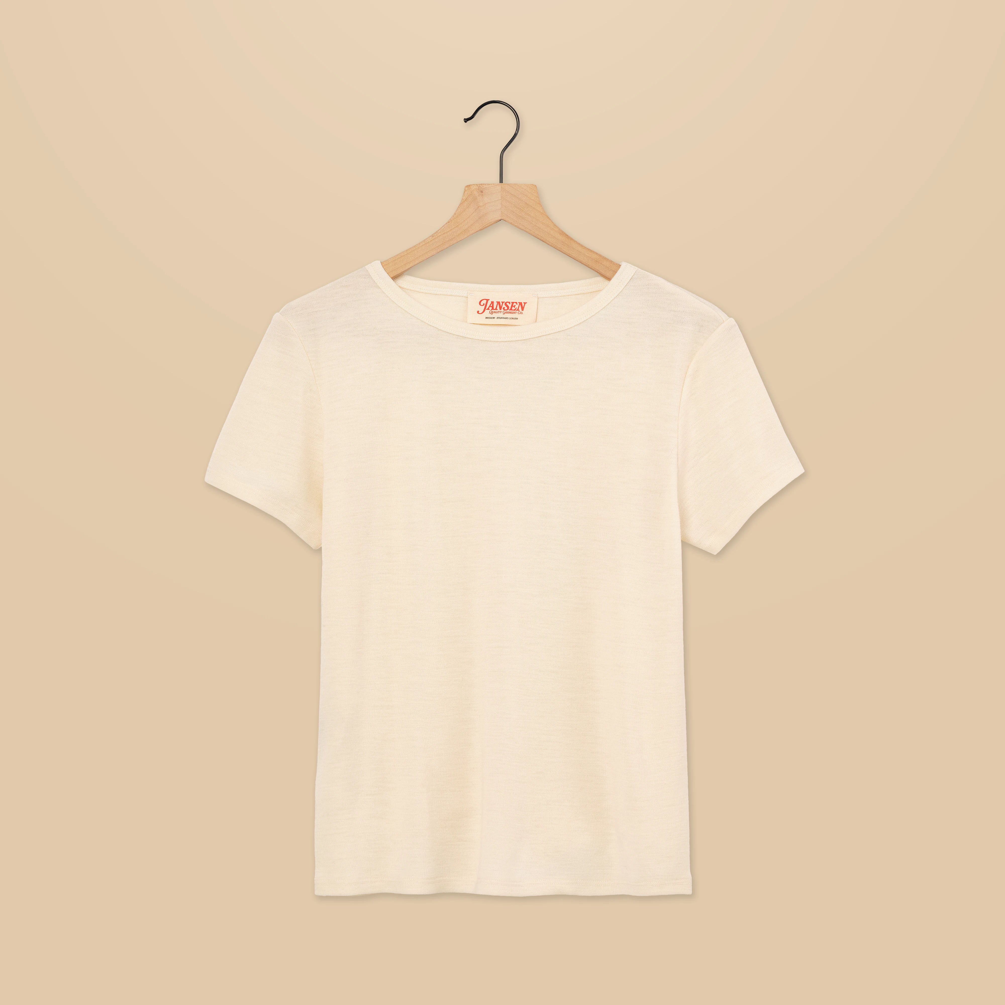 Natural white colored t-shirt on a wooden hanger against a beige background