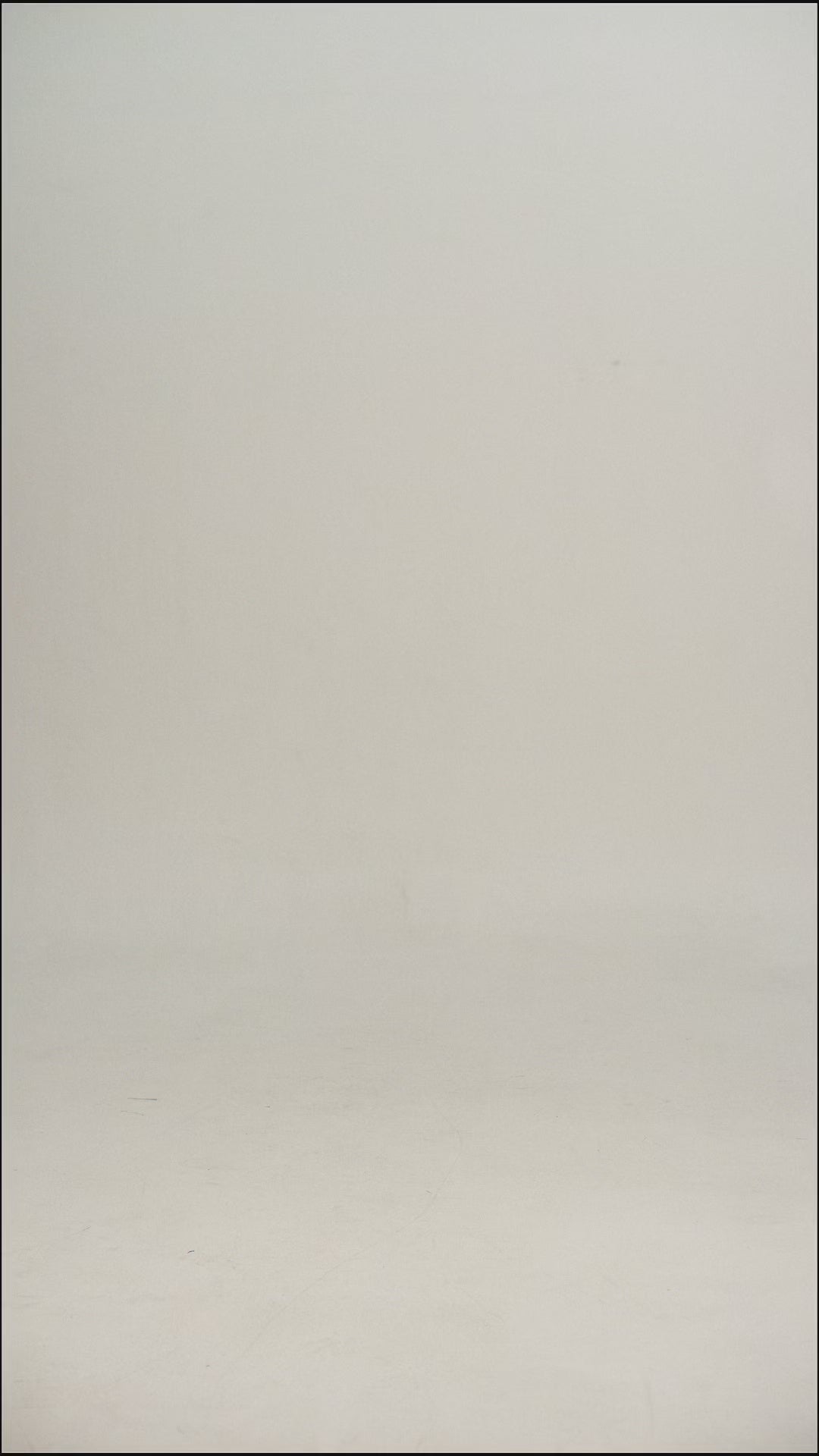 Video of a man wearing a white/cream wool tee shirt and blue jeans walking into frame, turning to show the tee, then walking out of frame.